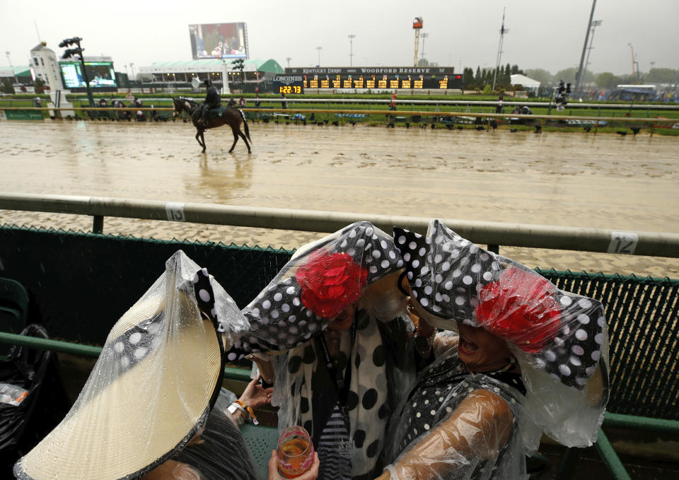 <p>Fans huddle under plastic before the 144th running of the Kentucky Derby horse race at Churchill Downs Saturday, May 5, 2018, in Louisville, Ky. (Photo: Charlie Riedel/AP) </p>