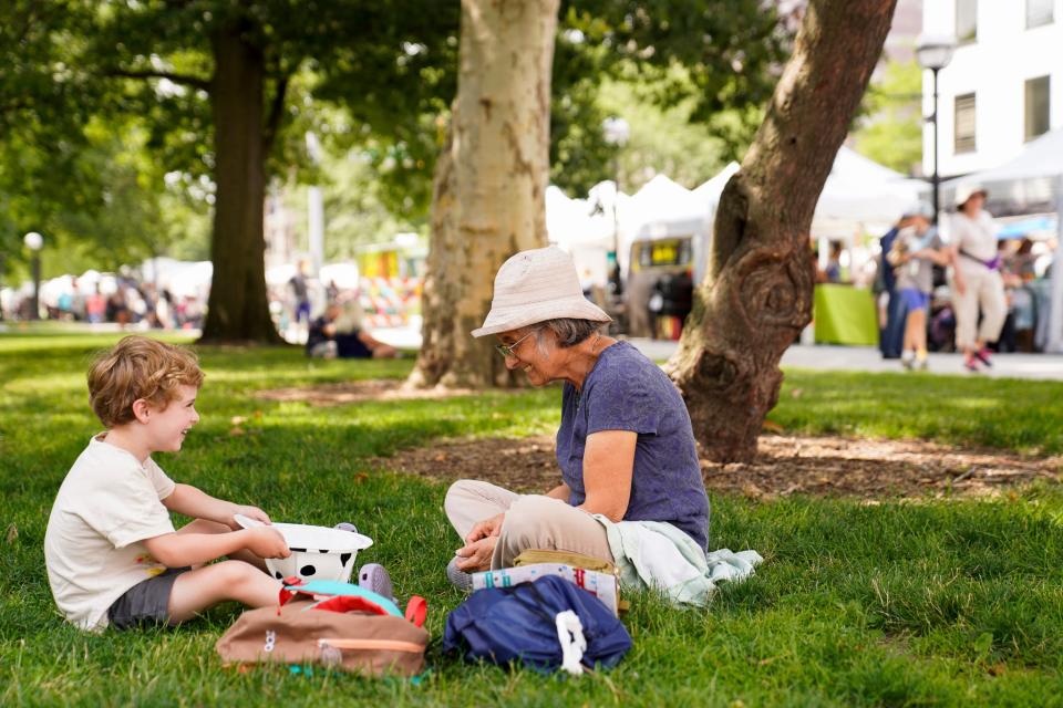 Arthur Keshet, 5, of Burns Park, and Jamie Keshet, of Austin, Texas enjoy a moment in the shade during the opening day of the Ann Arbor Art Fair in Ann Arbor on Thursday, July 20, 2023. The 3-day fair features almost 1,000 artists and draws in close to half a million attendees each year.