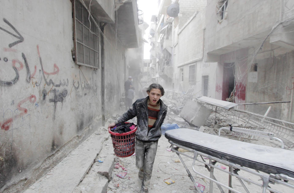 A boy carries his belongings at a site hit by what activists said was a barrel bomb dropped by forces loyal to Syria's President Bashar al-Assad in Aleppo's al-Fardous district, Syria on April 2, 2015.