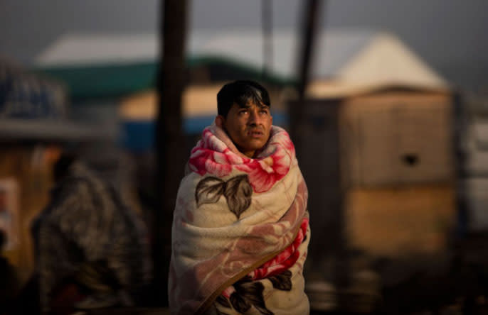 Die Evakuierung des Flüchtlingscamps in Calais hält immer noch an. Einer der Flüchtlinge steht, in eine Decke gehüllt, neben seinem abgebrannten Zelt. Seit Montag läuft in der Notunterkunft, die in Frankreich als Schandfleck in der Flüchtlingspolitik gilt, die Massenevakuierung. (Foto: Emilio Morenatti/AP)