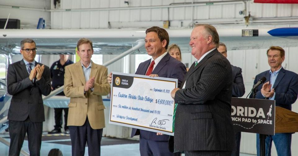 Florida Gov. Ron DeSantis presents Eastern Florida State College President Jim Richey, at right, with a ceremonial $6.6 million check, signifying funding for workforce development training at the college.