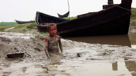 An undated video grab taken from the documentary film “Thirty Million” shows a young child bathing in muddy waters on Hatiya Island, Bangladesh. Raw Cinematics Production/Handout via Reuters