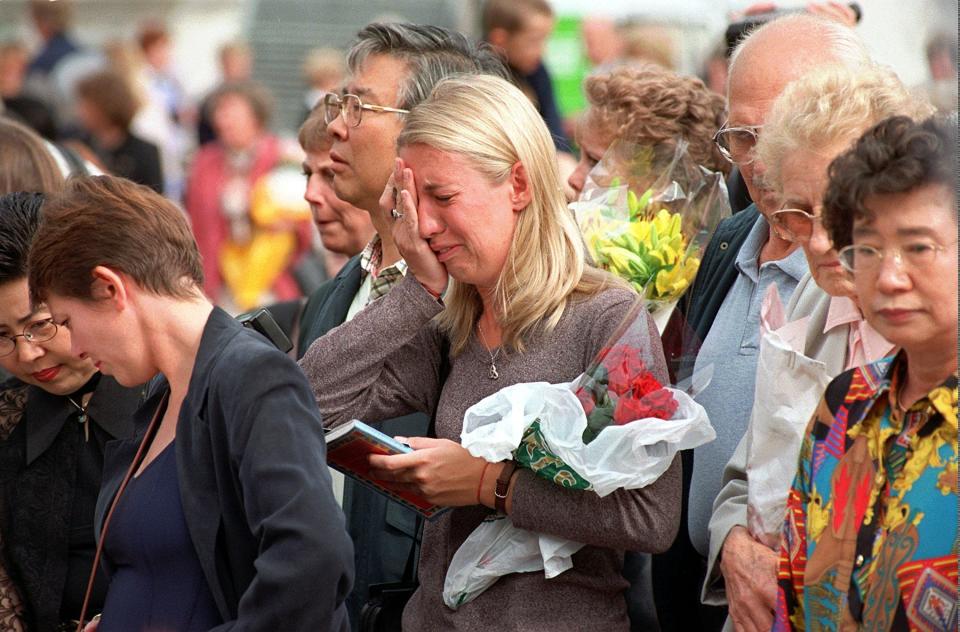 FILE - A crowd of mourners react as they view some of the mementos left in honor of Princess Diana at Buckingham Palace, in London, Friday Sept. 5, 1997. (AP Photo/Santiago Lyon, File)