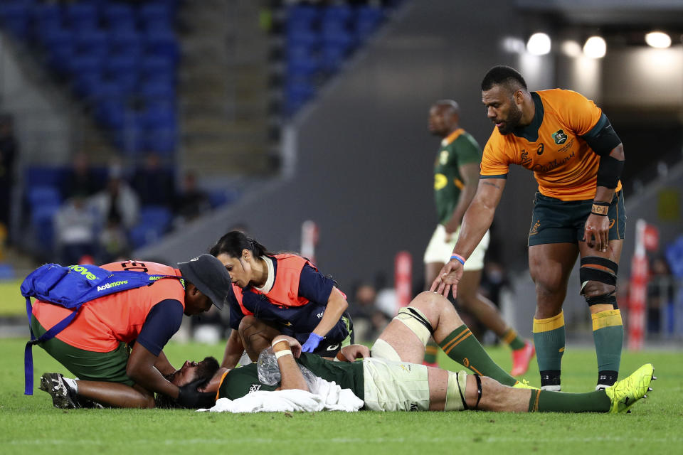 Australia's Samu Kerevi, right, checks on South Africa's Lood de Jager, bottom, as he is attended to by medical staff during their Rugby Championship match on Sunday, Sept. 12, 2021, Gold Coast, Australia. (AP Photo/Tertius Pickard)