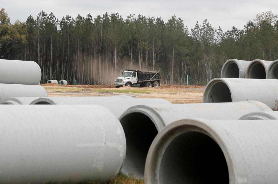 Dump trucks move dirt at the site of a new commercial and residential development in Guyton.