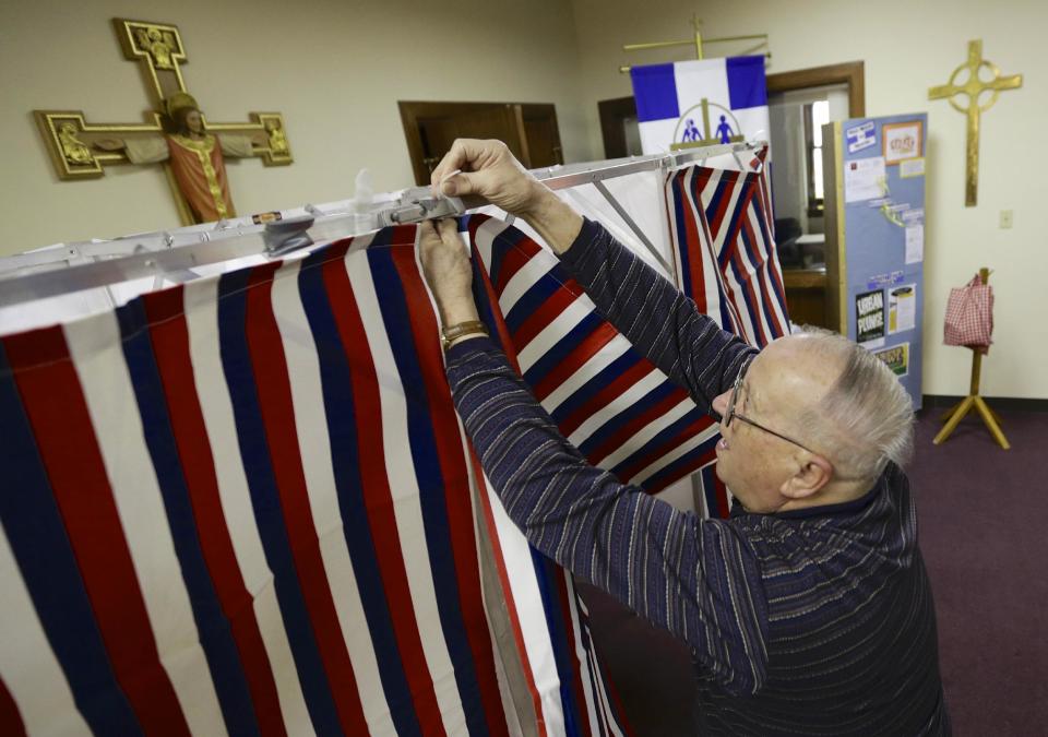 Election official Robert Buresh attaches the curtain to a polling booth at the Salem Lutheran Church polling station in Fremont, Neb., Tuesday, Feb. 11, 2014. Fremont voters are voting on whether to scrap the city's housing restrictions that were supposed to make it hard for people living in the country illegally to live there. This new vote on the ordinance voters approved in 2010 was scheduled because city leaders are worried about possibly losing federal grants and racking up big legal bills defending the law. (AP Photo/Nati Harnik)