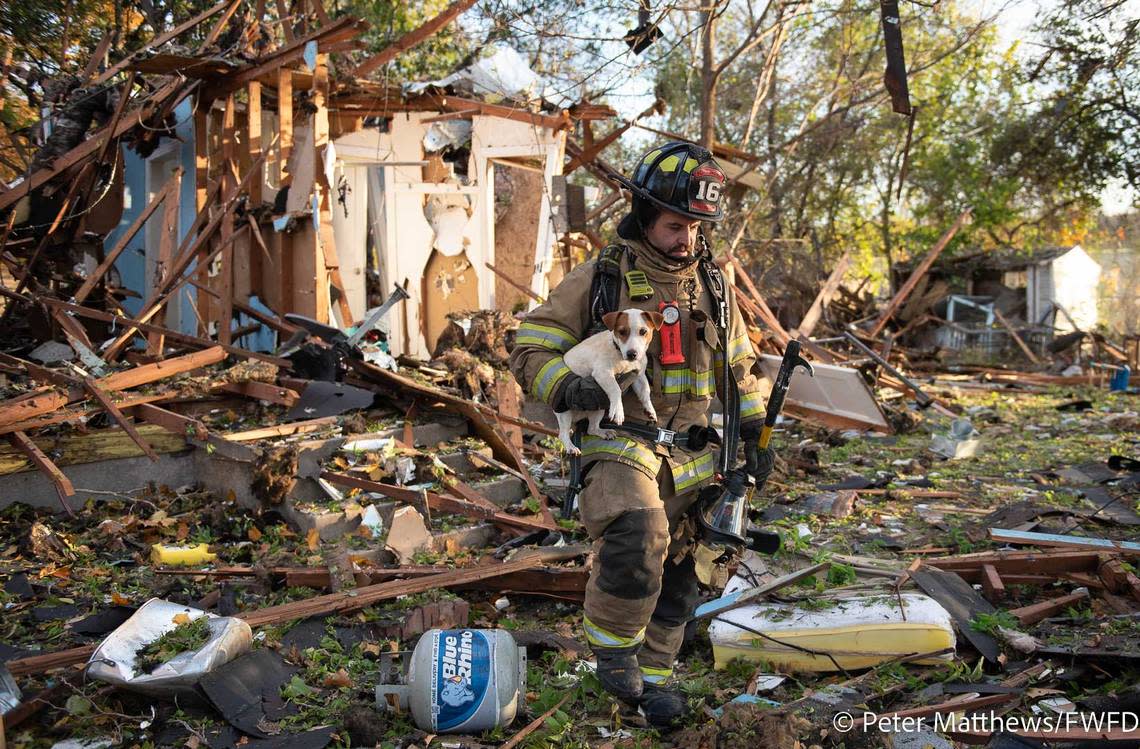 A firefighter carries a dog away from the remains of a house that exploded in Westworth Village on Dec. 1, 2022.