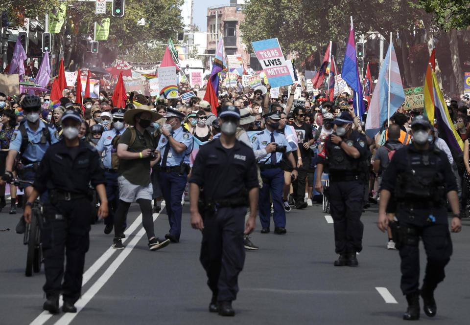 Hundreds of protesters march behind a row of police in Sydney, Saturday, March 6, 2021, ahead of the annual Gay and Lesbian Mardi Gras. The protesters say they want to restore the protest roots of Mardi Gras and challenge systems of injustice. (AP Photo/Rick Rycroft)