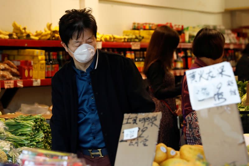 A man wears a face mask shopping at a market in the Chinatown section of San Francisco, California