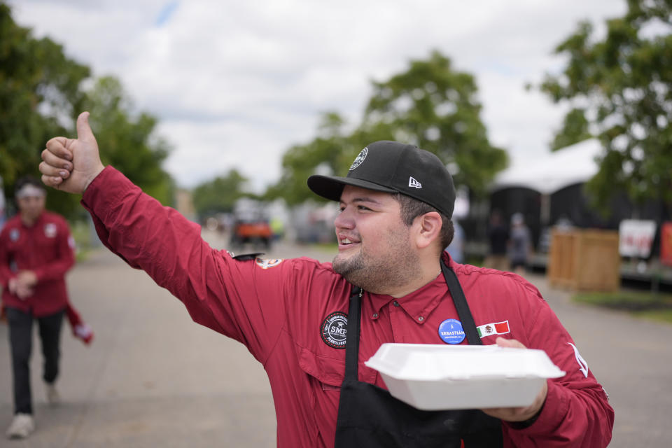 Sebastian De Alba, of the Sociedad Mexicana de Parrilleros team, gives a thumbs-up to fellow competitors as he delivers an entry to judges at the World Championship Barbecue Cooking Contest, Friday, May 17, 2024, in Memphis, Tenn. (AP Photo/George Walker IV)
