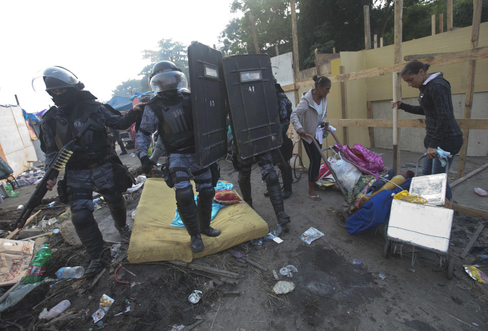 Dos mujeres transportan sus pertenencias mientras la policía entra en un área ocupada por invasores durante un desalojo en Río de Janeiro el viernes 11 de abril del 2014. (AP Foto/Silvia Izquierdo)