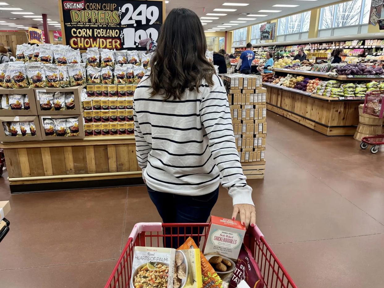 The writer leads a shopping cart full of items at Trader Joe's