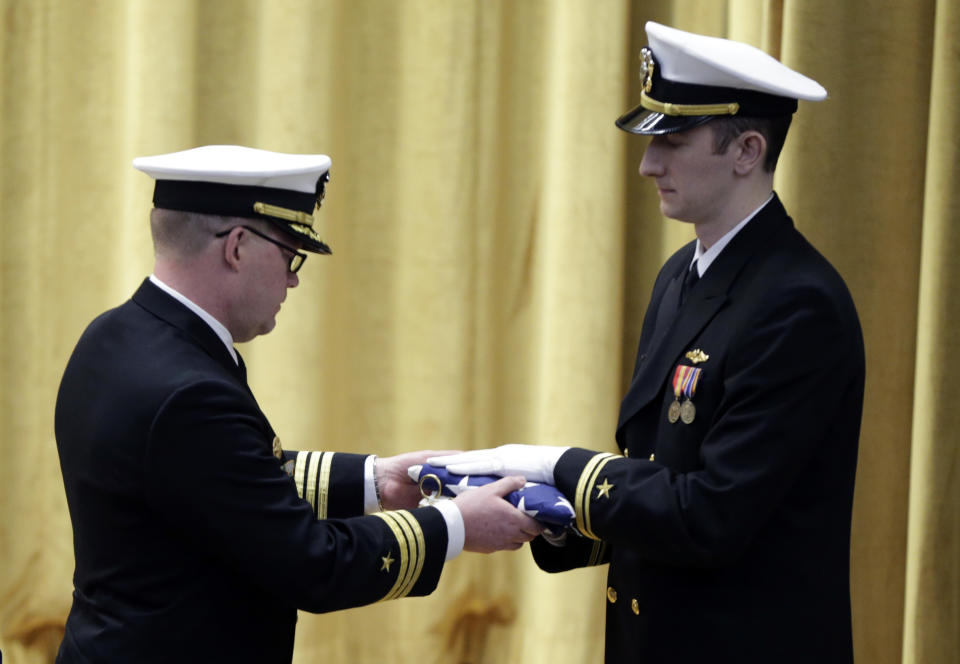 Commander Rolf Spelker, left, receives the commission pennant at the decommissioning ceremony for the fire-damaged USS Miami nuclear submarine at the Portsmouth Naval Shipyard, Friday, March 28, 2014, in Kittery, Maine. Rear Adm. Ken Perry, commander of the submarine Group Two in Groton, Conn., where the sub was based, acknowledged the seriousness of the event, but told the crowd they were there to celebrate the submarine and its crew’s achievements. “This is a tribute. This is a celebration of the ship’s performance and the superb contributions to the nation’s defense and this is how we’re going to treat it. So I expect to see some smiles out there,” he said. (AP Photo/Robert F. Bukaty)