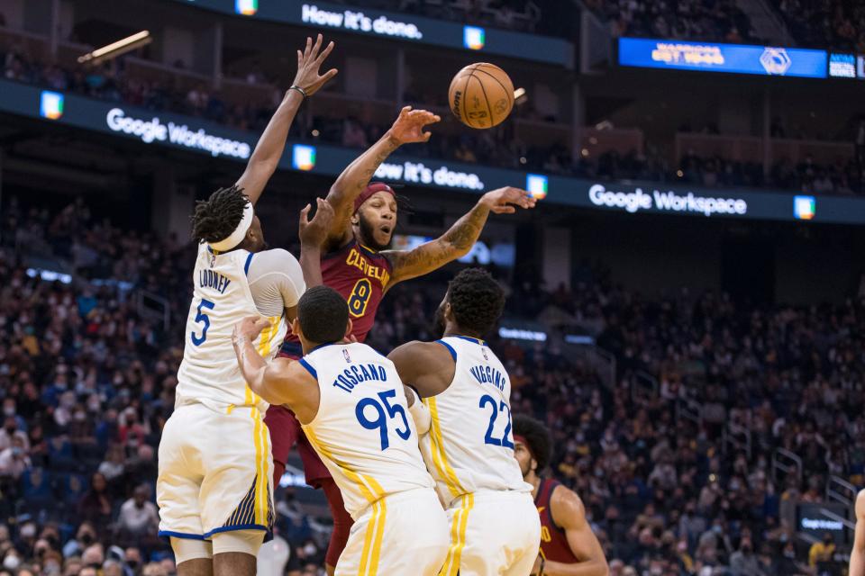 Cleveland Cavaliers forward Lamar Stevens (8) passes the ball over Golden State Warriors forward Andrew Wiggins (22), forward Juan Toscano-Anderson (95) and center Kevon Looney (5) during the first half of an NBA basketball game in San Francisco, Sunday, Jan. 9, 2022. (AP Photo/John Hefti)