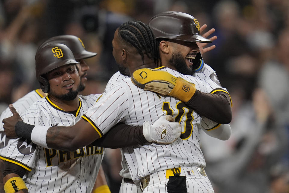 San Diego Padres' Fernando Tatis Jr., right, celebrates with teammates Luis Arraez, left, and Jurickson Profar, center, after scoring off a two-RBI double by Jake Cronenworth during the fifth inning of a baseball game against the Arizona Diamondbacks, Thursday, June 6, 2024, in San Diego. Arizona Diamondbacks' Lourdes Gurriel Jr. picked up a throwing error on the play. (AP Photo/Gregory Bull)