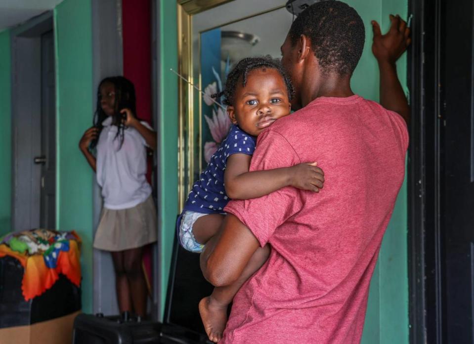 Mario Sauveur, de 32 años sostiene en brazos a su hijo mientras habla con su esposa sobre los planes de la urbanizadora para construir en el terreno donde ahora viven.
