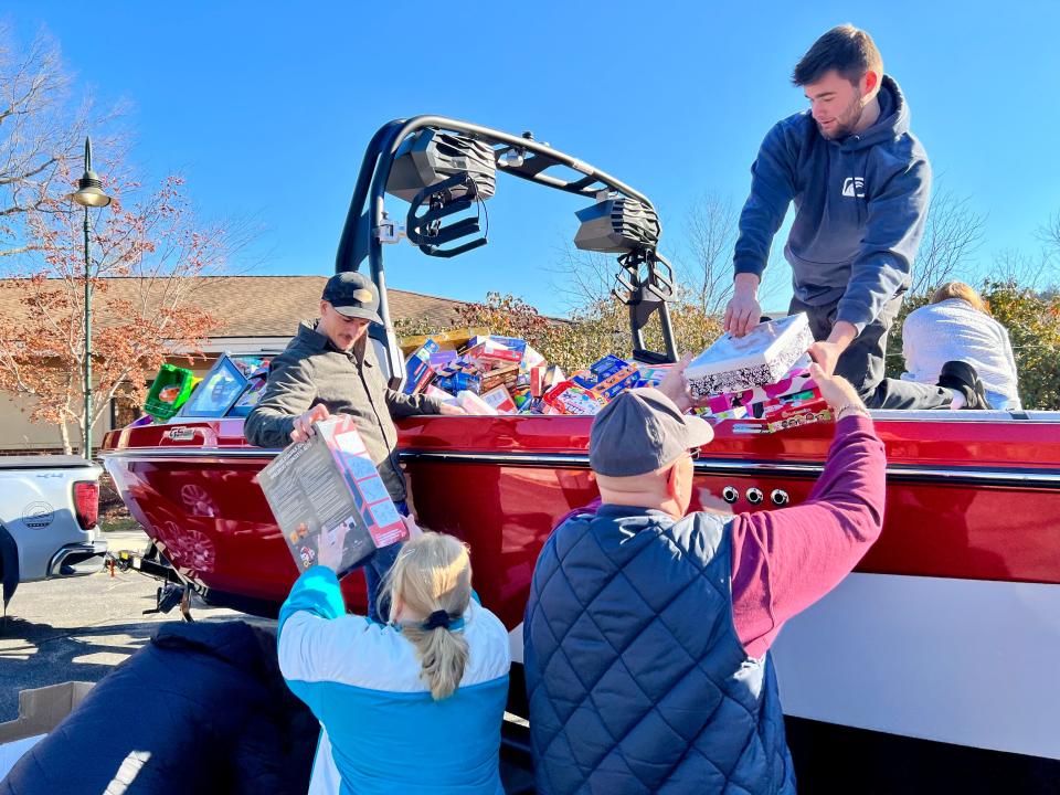 Off Shore Marine employees Kevin Cecchini and Joe McGavin unload toys collected from the company's Stuff the Boat initiative to benefit the Project Self-Sufficiency Season of Hope Toy Drive.