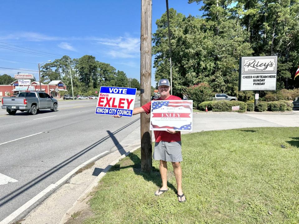 Lynn Childress holds up a sign outside Riley's Restaurant to show support for Kevin Exley.