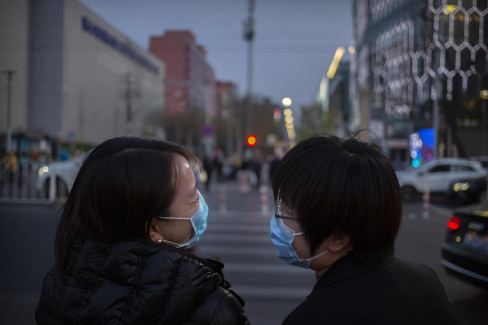 People wearing face masks to help curb the spread of the new coronavirus laugh as they cross an intersection in Beijing, Friday, April 10, 2020. China on Friday reported 42 new coronavirus cases, 38 of them imported, along with one additional death in the hardest-hit city of Wuhan. (AP Photo/Mark Schiefelbein)