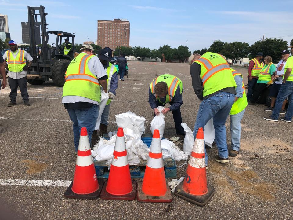 City of Amarillo employees hand out bags of sand to flood victims Tuesday. They started early in the morning and ran out of supplies quickly, but said more was coming from the Army Corps of Engineers in Canyon.