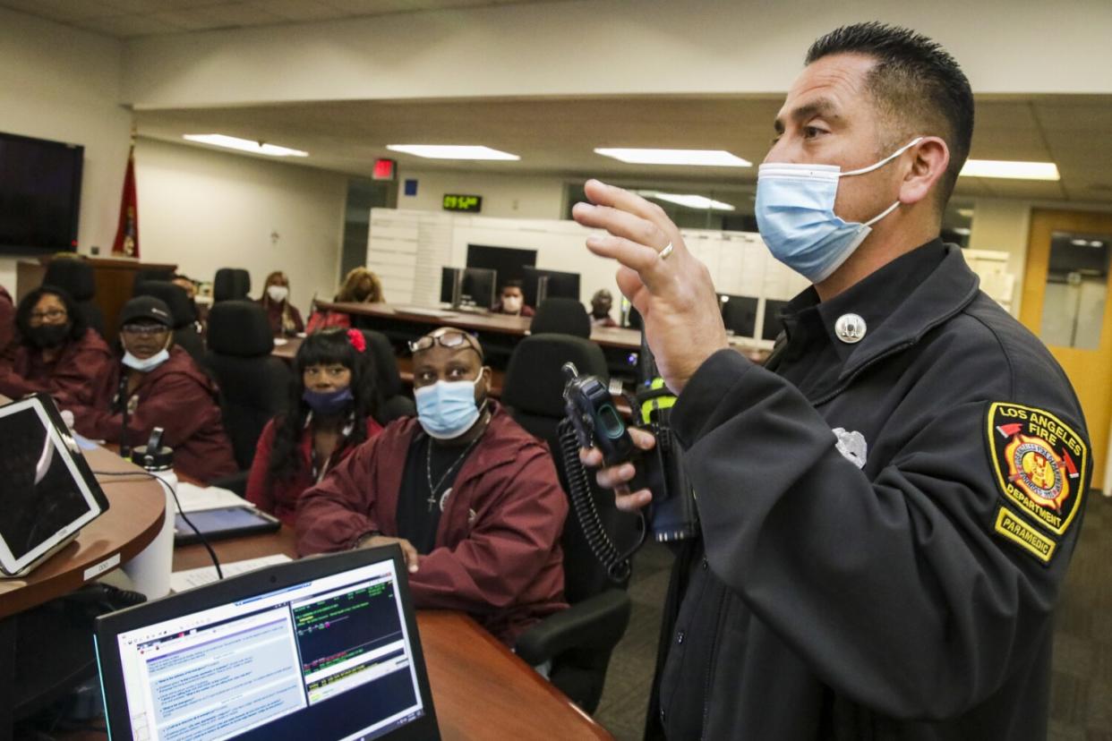 A man in a firefighter's uniform addresses a group of seated people