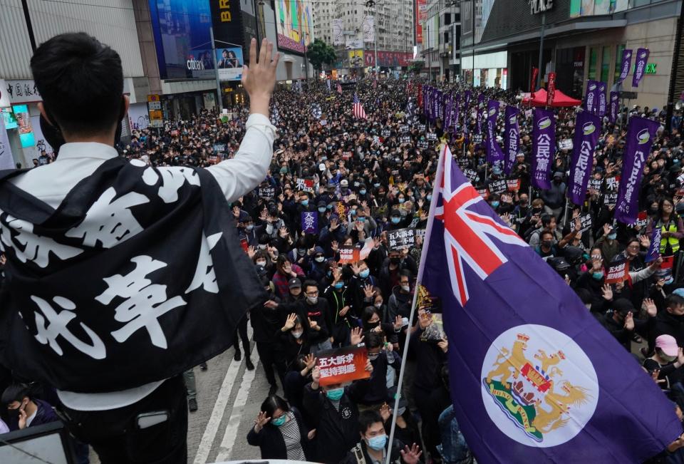 A man waves Hong Kong's colonial flag as people participate in their annual pro-democracy march on New Year's Day to insist their five demands be matched by the government in Hong Kong, Wednesday, Jan. 1, 2020. The five demands include democratic elections for Hong Kong's leader and legislature and a demand for a probe of police behavior during the six months of continuous protests. (AP Photo/Vincent Yu)