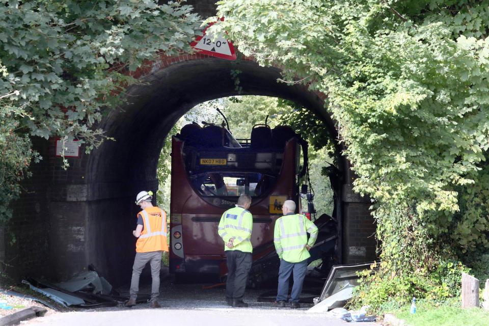 An engineer and police forensic vehicle examiners inspect the scene on Well House Lane in Winchester after three children were taken to hospital with serious injuries while 13 others suffered minor injuries after the school bus they were travelling in crashed into a railway bridge.