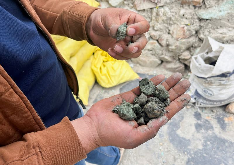 Artisan miner shows bags containing rocks with copper content next to an area where hundreds of artisan miners have found a rich seam of copper in Peru