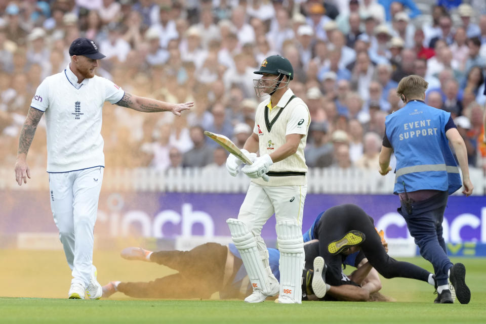 FILE England's Ben Stokes, left, and Australia's David Warner react as a Just Stop Oil protester is apprehended after they threw colored powder on the pitch during day one of the second Ashes Test cricket match at Lord's Cricket Ground, London, England, Wednesday, June 28, 2023. Britain is one of the world's oldest democracies, but some worry that essential rights and freedoms are under threat. They point to restrictions on protest imposed by the Conservative government that have seen environmental activists jailed for peaceful but disruptive actions. (AP Photo/Kirsty Wigglesworth, File)
