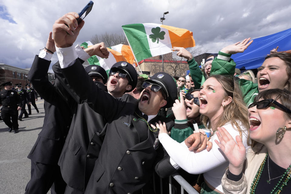 A group of firemen from around the United States pose for a selfie with spectators while marching in the St. Patrick's Day parade, Sunday, March 17, 2024, in Boston's South Boston neighborhood. (AP Photo/Steven Senne)