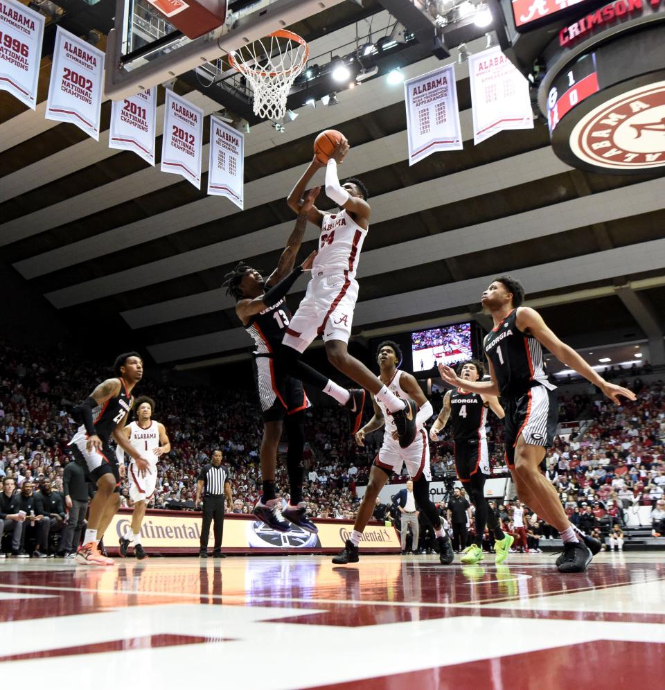 Feb 18, 2023; Tuscaloosa, Alabama, USA;  Alabama forward Brandon Miller (24) soars through the lane to score over Georgia guard Mardrez McBride (13) at Coleman Coliseum. Mandatory Credit: Gary Cosby Jr.-USA TODAY Sports