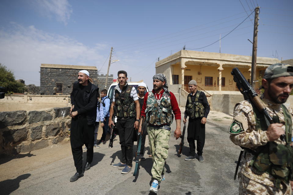 In this Thursday, Oct. 4, 2018, photo, young Druze armed men, who carry weapons to defend their village from Islamic State attack, patrol the village of Rami in the southern province of Sweida, Syria. Three months after a stunning Islamic State attack on a southeastern corner of Syria in which more than 200 people were killed and 30 women and children abducted, tensions are boiling over, and young men are taking up arms. It is a stark change for a province that managed to stay on the sidelines of the seven-year Syrian war and where most villagers worked grazing livestock over surrounding hills. (AP Photo/Hassan Ammar)