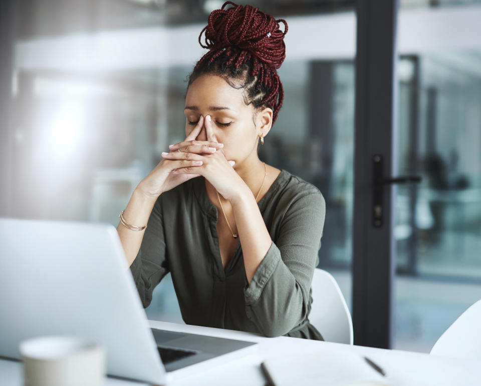 a woman with her hands on her face looking at a laptop