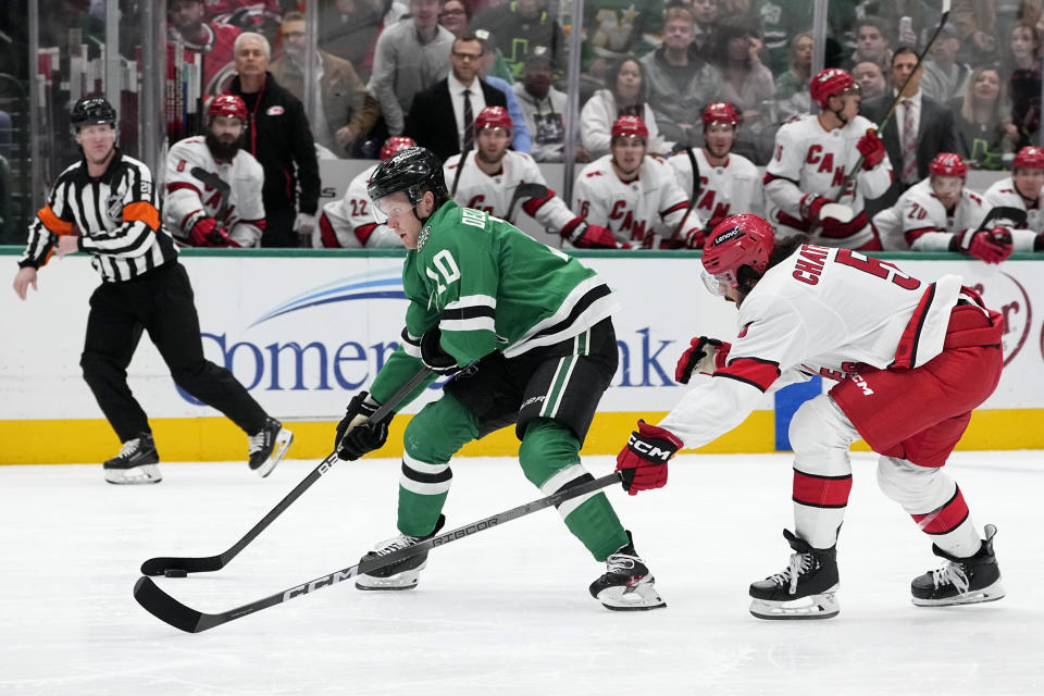 Dallas Stars center Ty Dellandrea (10) lines up to take a shot as Carolina Hurricanes' Jalen Chatfield (5) reaches in to disrupt the attempt in the first period of an NHL hockey game in Dallas, Tuesday, Feb. 13, 2024. (AP Photo/Tony Gutierrez)