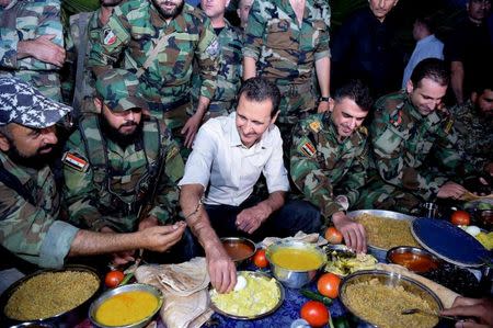 Syria's President Bashar al-Assad (C) joins Syrian army soldiers for Iftar in the farms of Marj al-Sultan village, eastern Ghouta in Damascus, Syria, in this handout picture provided by SANA on June 26, 2016. SANA/Handout via REUTERS/File Photo