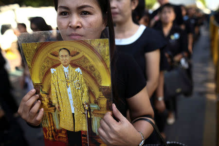 A mourner holds up a picture of Thailand's late King Bhumibol Adulyadej as she waits in line to offer condolences at the Grand Palace in Bangkok, Thailand, October 20, 2016. REUTERS/Athit Perawongmetha