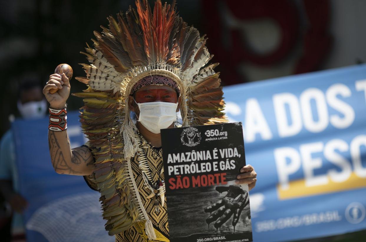 Co-author of this article, Chief Ninawa, hereditary Chief of the Huni Kui Indigenous people of the Amazon, holds a sign that says: 'Amazon is life, petroleum and gas is death' outside a hotel in Rio de Janeiro, Brazil. (AP Photo/Silvia Izquierdo)