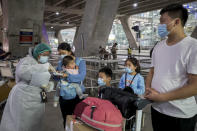 A public health worker gathers information from Chinese tourists from Shanghai, who arrived at Suvarnabhumi airport on special tourist visas, in Bangkok, Thailand, Tuesday, Oct. 20, 2020. Thailand on Tuesday took a modest step toward reviving its coronavirus-battered tourist industry by welcoming 39 visitors who flew in from Shanghai, the first such arrival since normal traveler arrivals were banned almost seven months ago. (AP Photo/Wason Wanichakorn)