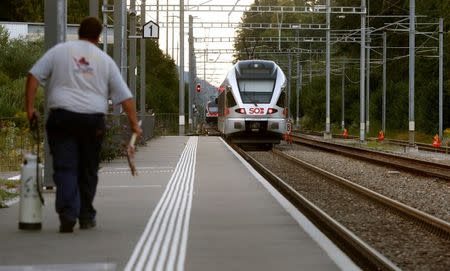 A cleaning worker walks on a platform after a 27-year-old Swiss man's attack on a Swiss train (back) at the railway station in the town of Salez, Switzerland August 13, 2016. REUTERS/Arnd Wiegmann