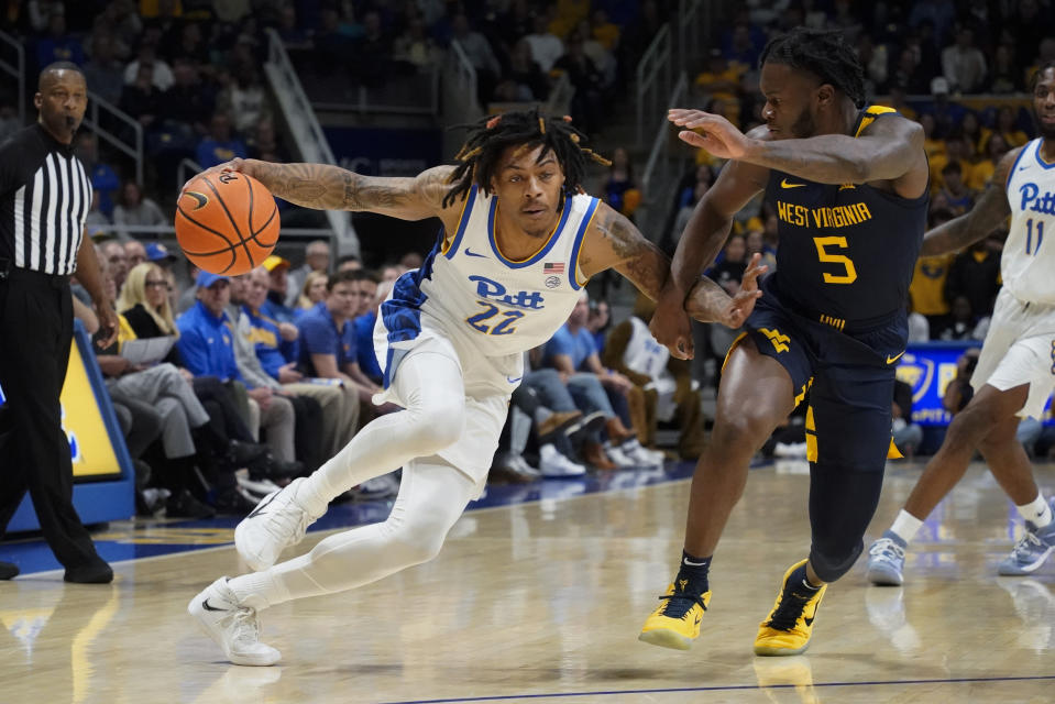 Pittsburgh's Nike Sibande (22) drives against West Virginia's Joe Toussaint (5) during the first half of an NCAA college basketball game, Friday, Nov. 11, 2022, in Pittsburgh. (AP Photo/Keith Srakocic)