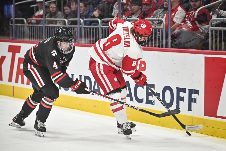 Wisconsin forward William Whitelaw (8) handles the puck behind the net as Northeastern defenseman Pito Walton (4) pursues during the first period of the championship game of the Kwik Trip Holiday Face-Off on Friday, December 29, 2023, at Fiserv Forum in Milwaukee, Wisconsin.