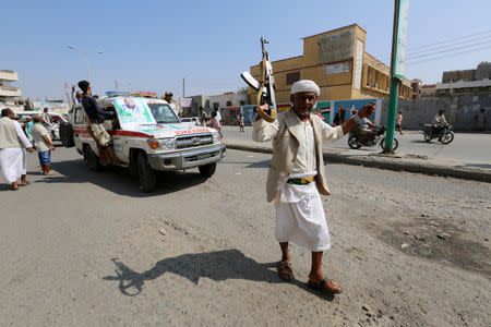 An armed man walks past an ambulance ferrying the coffins of victims who were killed by shells that hit a house in Hodeidah, Yemen December 10, 2018. REUTERS/Abduljabbar Zeyad