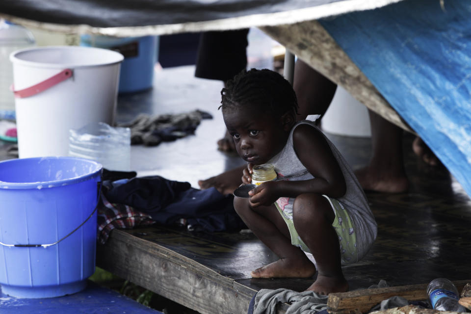 A migrant child peeks out from under a tent at a migrant camp amid the new coronavirus pandemic, in Lajas Blancas, Darien province, Panama, Saturday, Aug. 29, 2020. Panama's government says it has built, along with the U.N. High Commissioner for Refugees, a new camp with better shelter on the outskirts of Meteti where it hopes to soon move 400 migrants, especially families with young children. (AP Photo/Arnulfo Franco)