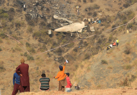 A boy plays with a paper plane near the site of a plane crash in the vilage of Saddha Batolni near Abbotabad, Pakistan December 8, 2016. . REUTERS/Faisal Mahmood