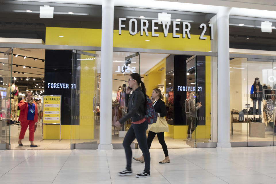 People walk in front of a Forever 21 clothing store, Monday, Sept. 30, 2019, in New York. Low-price fashion chain Forever 21, a one-time hot destination for teen shoppers that fell victim to its own rapid expansion and changing consumer tastes, has filed for Chapter 11 bankruptcy protection. (AP Photo/Mark Lennihan)
