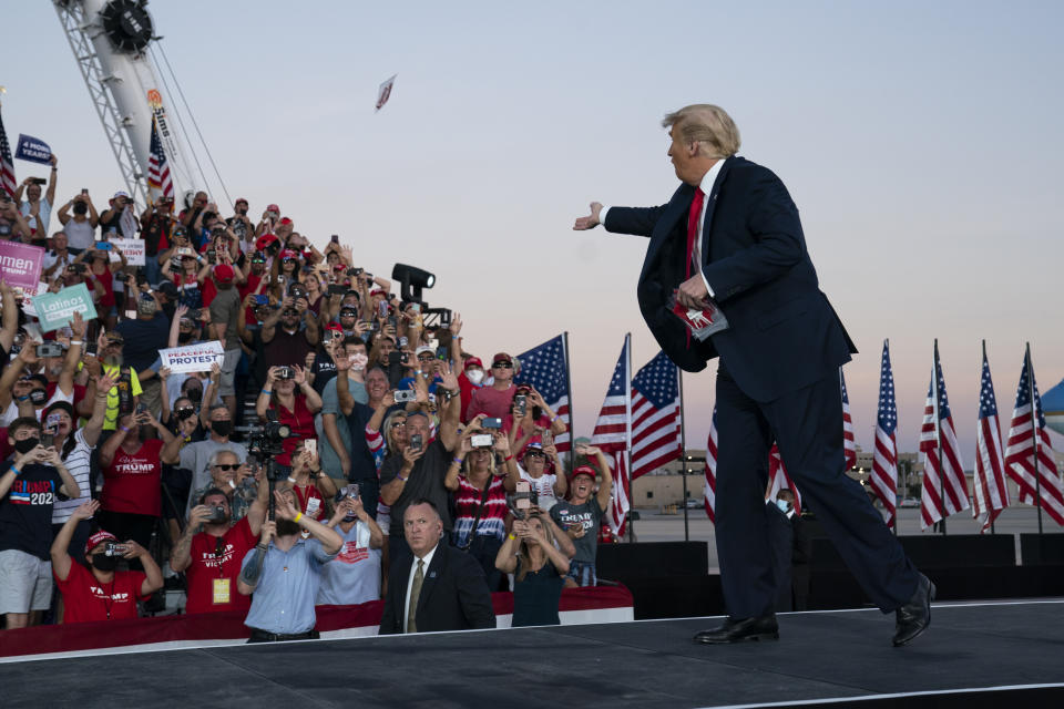 President Donald Trump throws face masks into the crowd as he arrives for a campaign rally at Orlando Sanford International Airport, Monday, Oct. 12, 2020, in Sanford, Fla. (AP Photo/Evan Vucci)