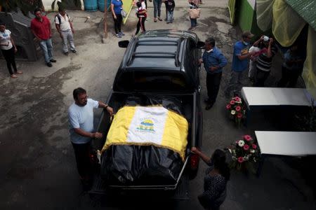 Relatives cover the bodies of Jason and Marielos Sanchez Mendez, the victims of a mudslide, with a flag, during a memoral in Santa Catarina Pinula, on the outskirts of Guatemala City, October 5, 2015. REUTERS/Jose Cabezas
