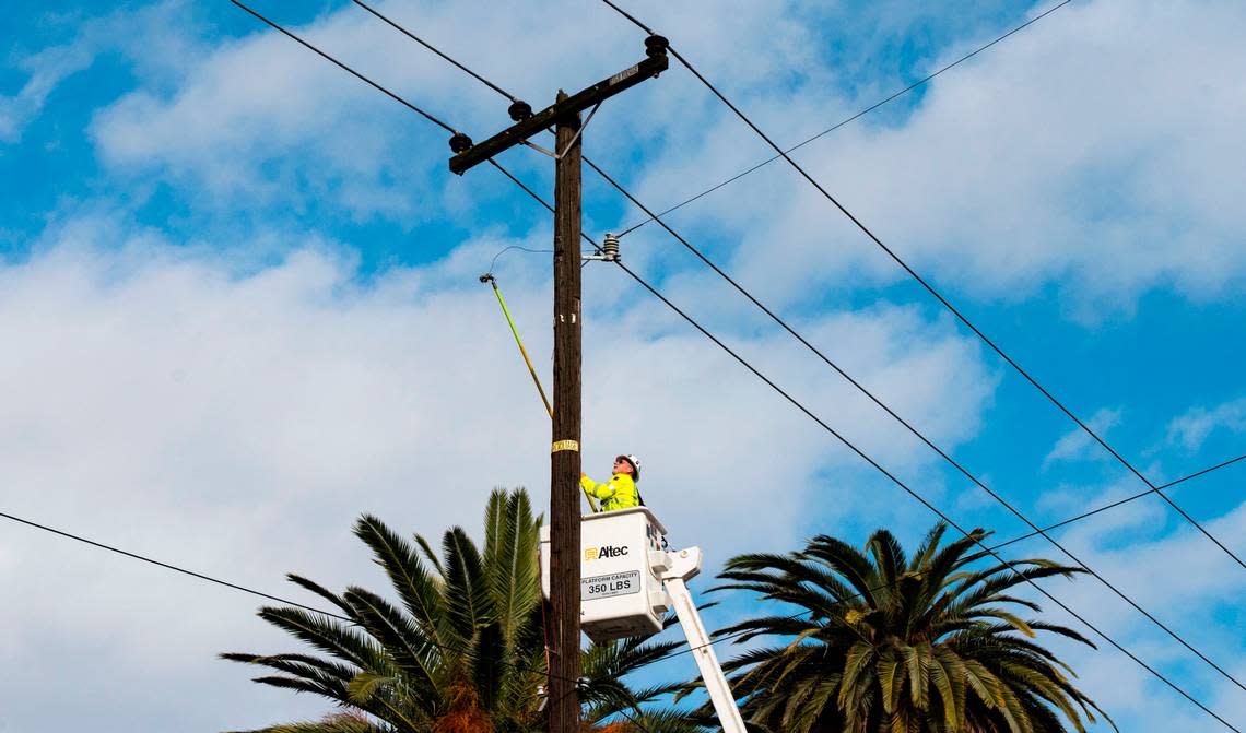 A SMUD worker attempts repairs to a power line on Riverside Boulevard in Land Park on Sunday, Jan. 8, 2022, after high winds downed trees and power lines across the street overnight.