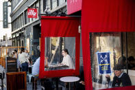 Savannah Daniels dines at The Dorian in San Francisco's Marina district Wednesday, Oct. 21, 2020. Plastic dividers separate diners from those at an adjacent restaurant. As the coronavirus pandemic transforms San Francisco's workplace, legions of tech workers have left, able to work remotely from anywhere. Families have fled for roomy suburban homes with backyards. The exodus has pushed rents in the prohibitively expensive city to their lowest in years. (AP Photo/Noah Berger)