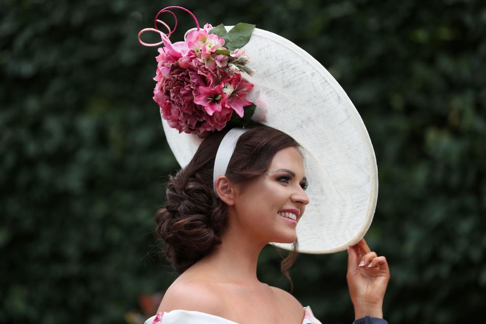 The red-and-white color palette of this hat matches this day one racegoer's dress.